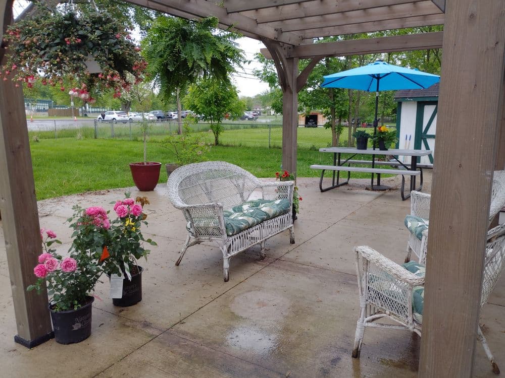 Cozy outdoor seating area with wicker chairs, flowers, and a blue umbrella. Perfect for relaxation.