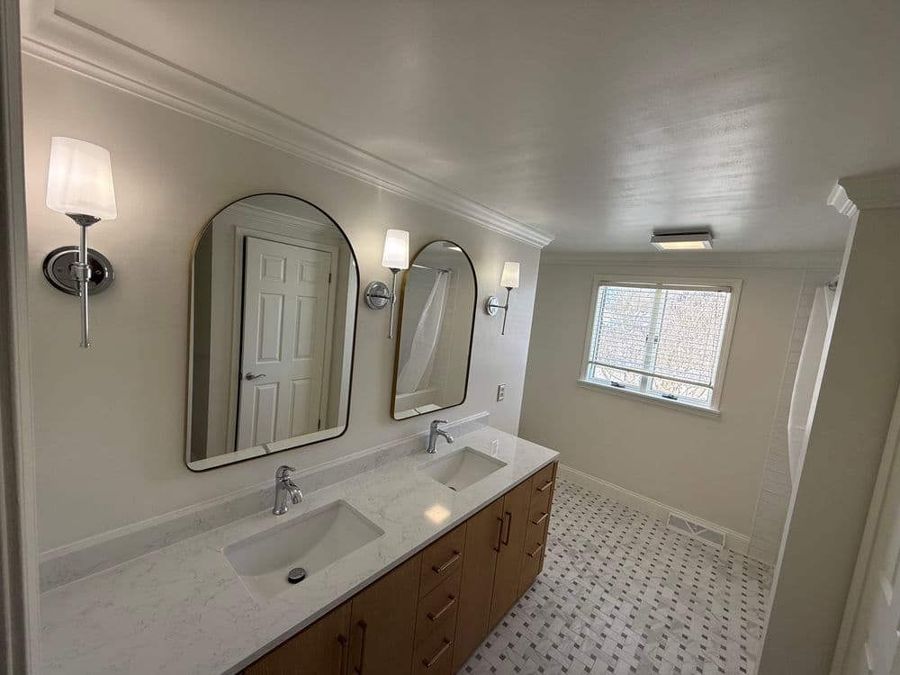 Modern bathroom with double sinks, large mirrors, and elegant lighting fixtures.