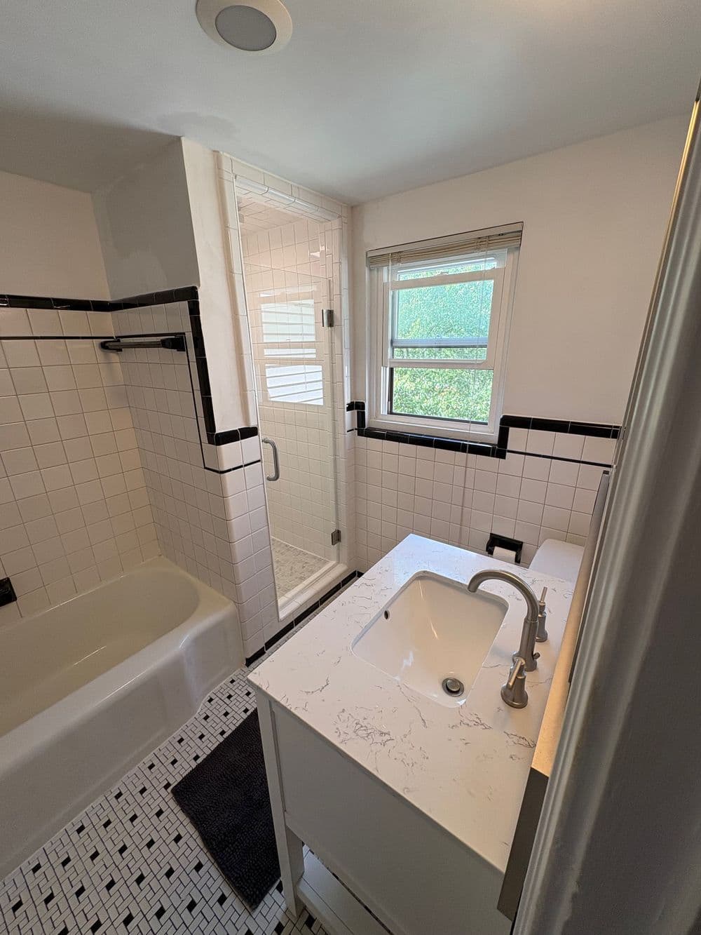 Modern bathroom with a shower, bathtub, and sleek vanity featuring a minimalist design.